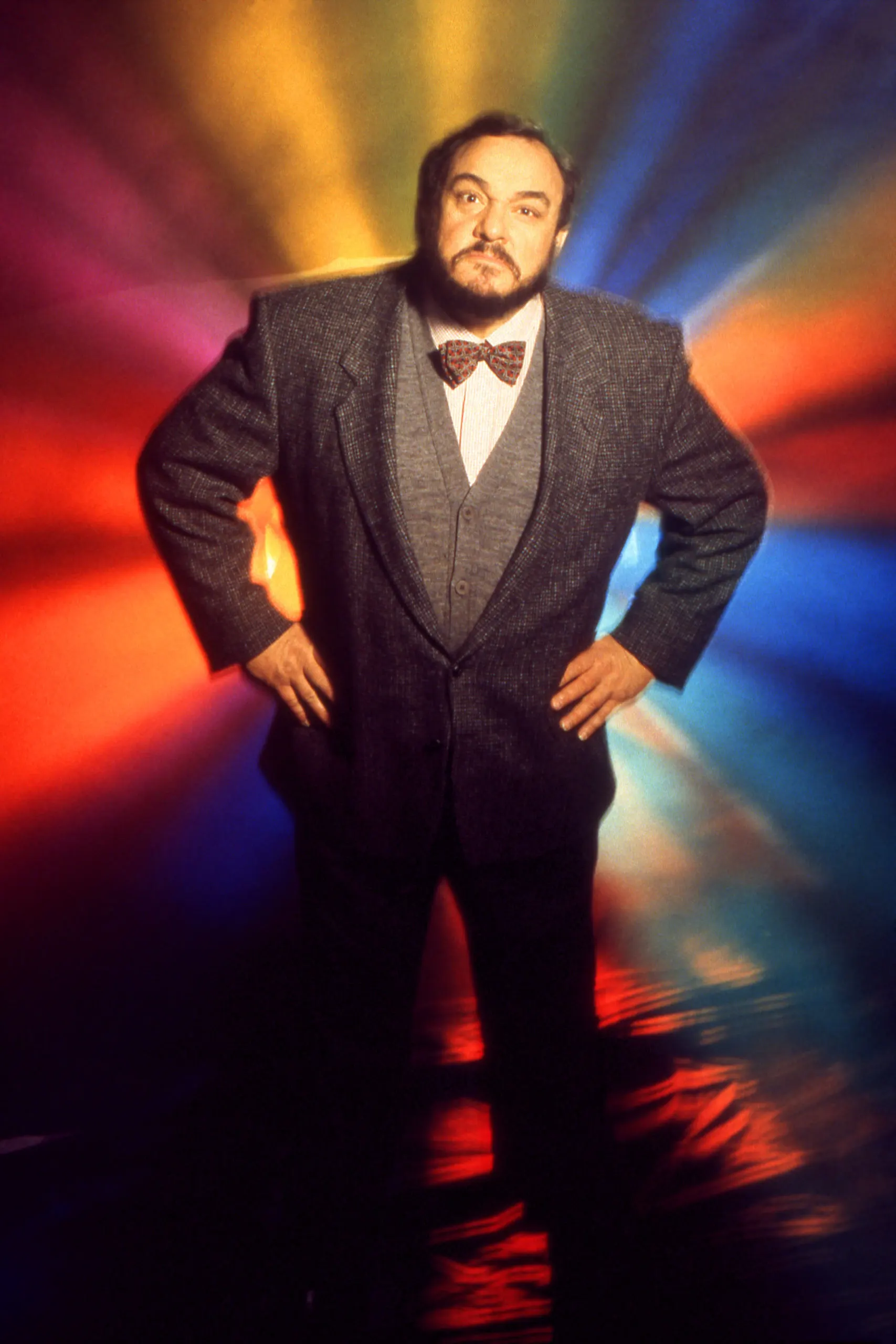 John Rhys-Davies as Professor Maximillian Arturo standing in front of a prism color background