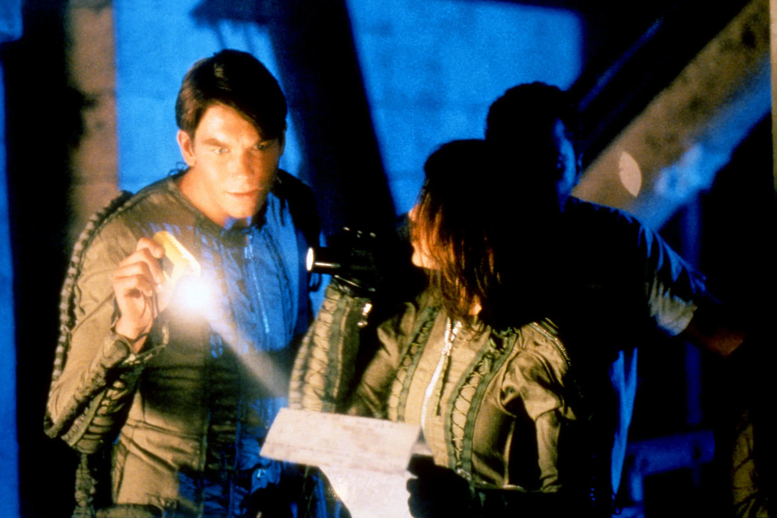 Promo photo from the episode Genesis with Quinn looking at a paper with a flashlight
