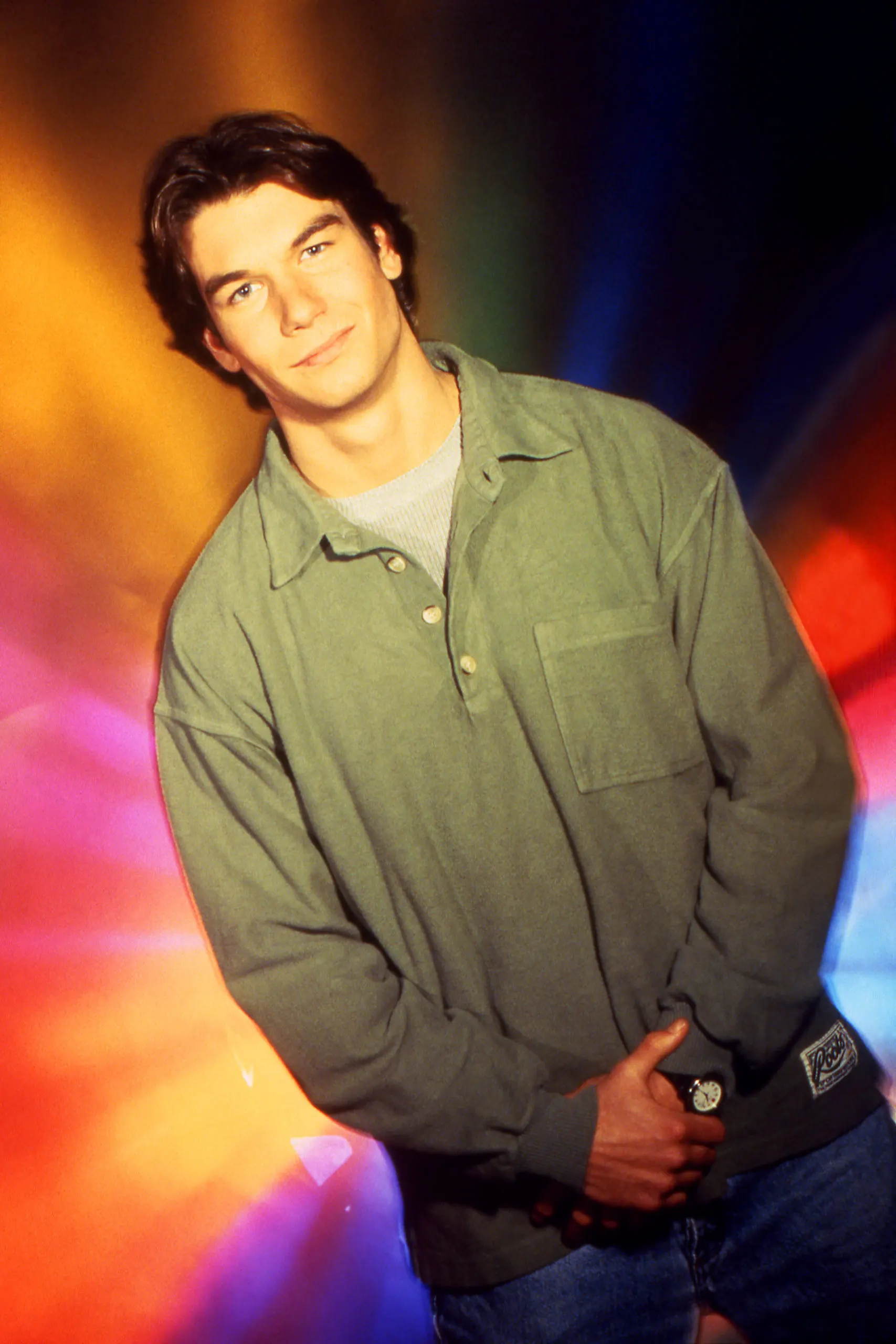 Jerry O'Connell as Quinn Mallory standing in front of a prism color background