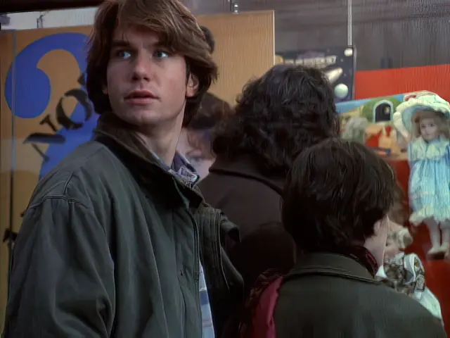Quinn looks over his shoulder while the Sliders look at a doll in the storefront window in the Sliders episode Love Gods