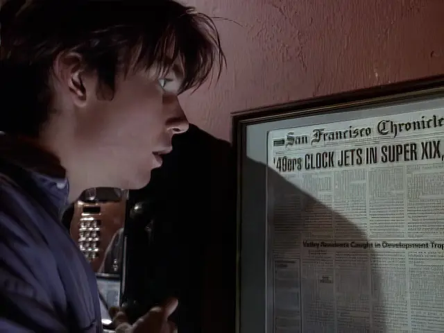 Quinn looking at a headline from the San Francisco Chronicle newspaper in the episode Post Traumatic Slide Syndrome