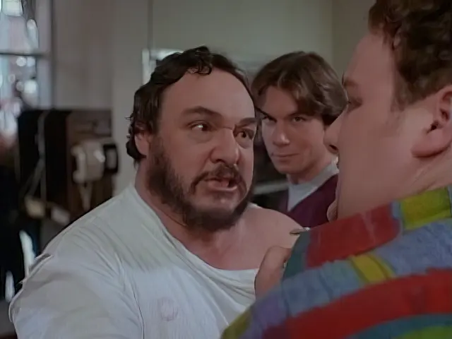 Professor Arturo grabs the hotel clerk (Will Sasso) by the shirt collar to insist he is not Luciano Pavarotti