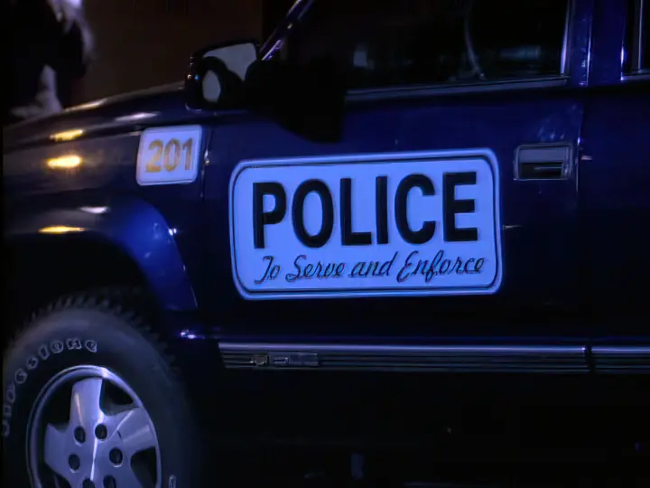 The slogan, "To Serve and Enforce" displayed on a police cruiser at night